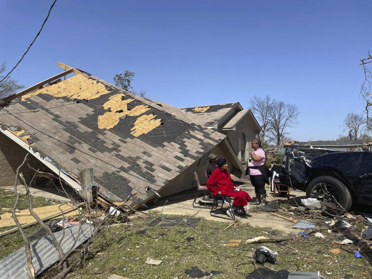 People sit in front of a damaged home in Silver City, Mississippi on Saturday. Photo: AP