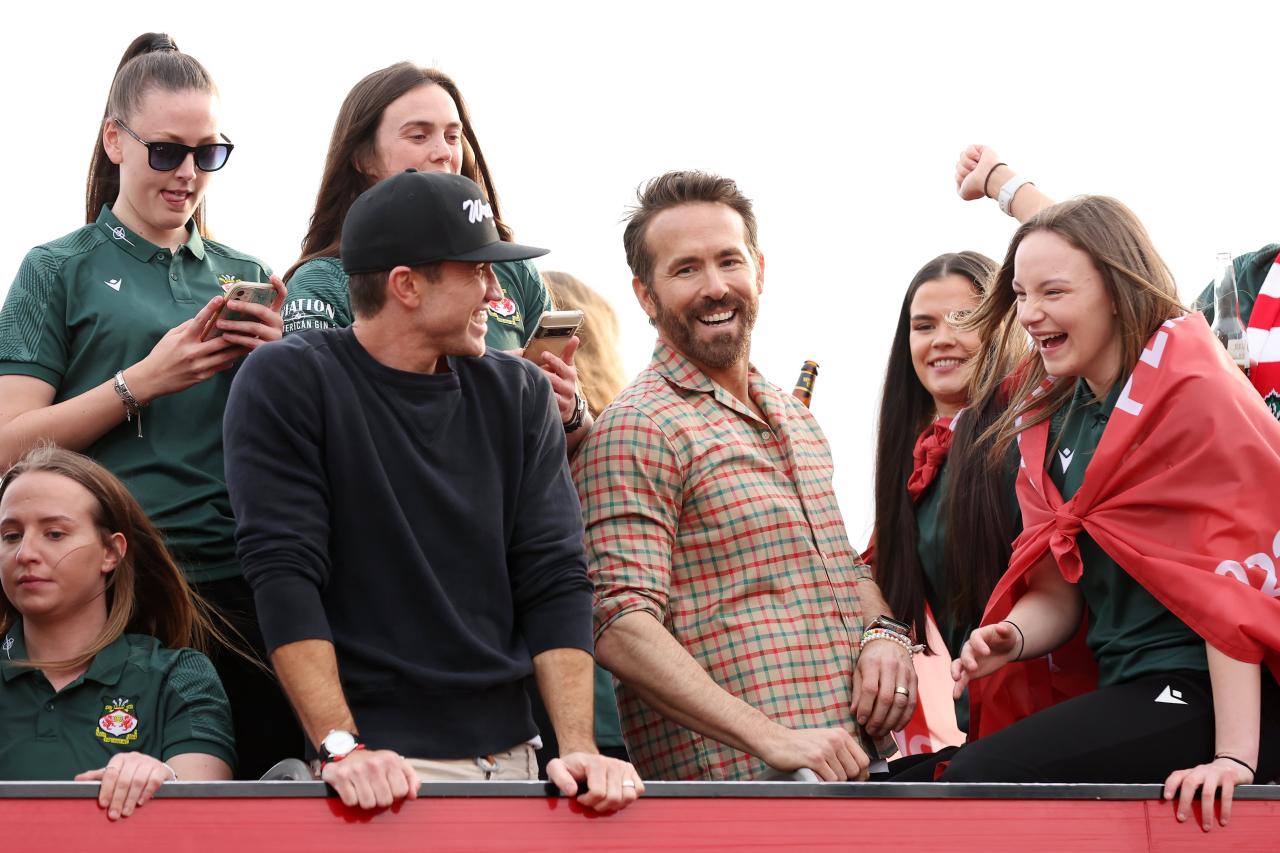 WREXHAM, Wales - May 2, 2023: Ryan Reynolds and Rob McElhenney, co-owners of Wrexham AFC, celebrate with the club's men's and women's teams during a bus parade following their respective title-winning seasons in the Vanarama National League and Genero Adran North.